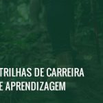 Imagem dos pés de duas pessoas caminhando na floresta e de um bastão de caminhada tocando o chão, além do texto trilhas de carreira e aprendizagem.